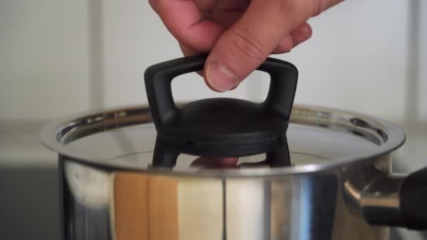 男性手打开和关闭锅盖用开水沸腾 — 图库视频影像