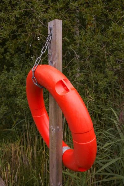 Red life ring buoy hanging from a wooden pole, close up