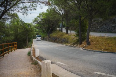 Hırvatistan 'da dolambaçlı bir dağ yolunda giden beyaz turist otobüsü