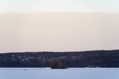 Donmuş göl manzarası. Uzakta buzda balık tutan insanlar var. Lahti, Finlandiya.