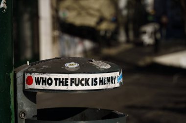 Sticker on a trashcan saying - Who the fuck is Henry? in Lisbon, Portugal. February 1, 2024.