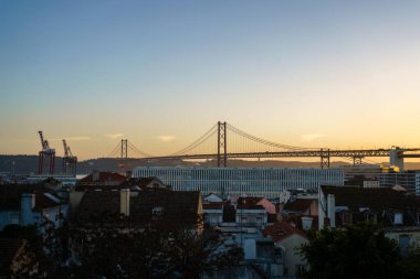 Lizbon, Portekiz 'deki 25 De Abril Köprüsü ve Limanı üzerinde gün batımı. 2 Şubat 2024.