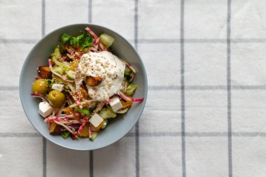 Tohum, sos ve proteinle kaplı bir kase taze salata. Üst görünüm.
