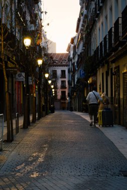 Madrid, İspanya. 11 Şubat 2024 - İspanya 'nın Madrid caddelerinde akşamları iki kişi bavullarını yuvarlıyor.