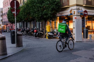 Sevilla, İspanya. 4 Şubat 2024 - Sevilla 'nın tarihi sokaklarında Uber Eats teslimatçısı bisikletçi