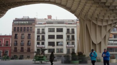 Sevilla, İspanya. 7 Şubat 2024 - Metropol Şemsiyesi, ahşap yapının altındaki meydanda yürüyen insanlar