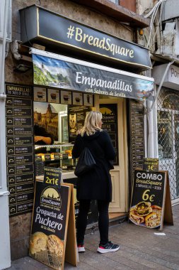 Sevilla, İspanya. 4 Şubat 2024 - BreadSquare Empanadas restoranını ziyaret eden kadın