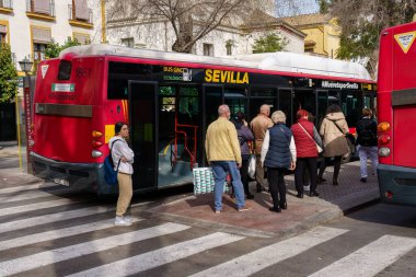 Sevilla, İspanya. 5 Şubat 2024 - Kırmızı şehir otobüsüne binen yolcular