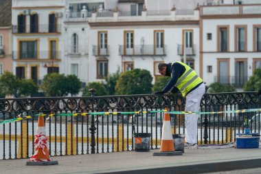 Sevilla, İspanya. 5 Şubat 2024 - Köprü rayı boyayan işçi