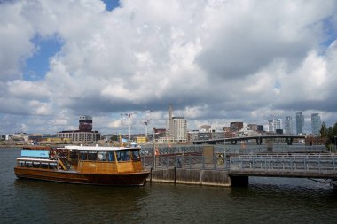 Helsinki, Finlandiya. 29 Haziran 2024 - Ahşap tekne Korkeasaari 'ye yanaştı, arka planda şehir manzarası var.