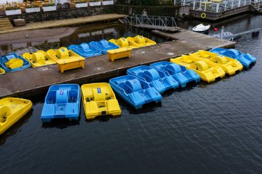 Stockholm, İsveç. 15 Nisan 2024 - Mavi ve sarı pedallı botlar Djurgardsbron restoranının iskelesine yanaştı