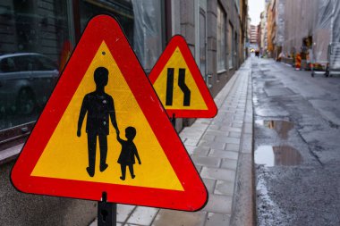 Şehir caddesinde sarı ve kırmızı bir yaya uyarısı.