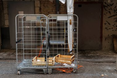 Binanın önünde tahta kutuları olan iki metal yük arabası.
