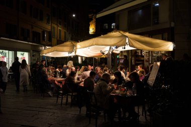 Bolonya, İtalya. 6 Ekim 2024 - İnsanlar akşam geç saatlerde açık bir kafede yemek yiyorlar