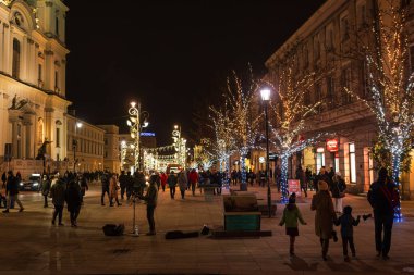 Warsaw, Poland. January 25, 2025 - People walking on Krakowskie Przedmiescie with festive light decorations at night. clipart