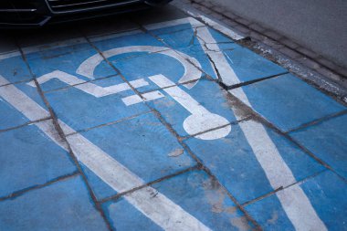 Engelliler için park yeri, eski, yıpranmış bir kaldırımda işaretlenmiş..
