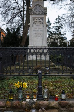 Bulutlu bir günde tarihi bir mezarlıkta mumlar ve çiçeklerle anılıyor.