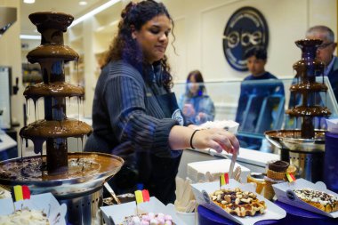 Brüksel, Belçika. 20 Mart 2025 - Obe Belçika waffle dükkanında çikolata ikram eden işçi.
