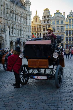 Brüksel, Belçika. 20 Mart 2025 Grand Place 'e park edilmiş elektrikli araba turistler için geleneksel at arabalarının yerini aldı..
