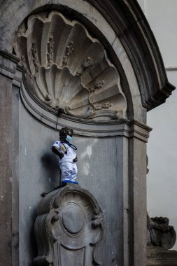 Brüksel, Belçika. 20 Mart 2025 - Manneken Pi, Yaşlı Jerome Duquesnoy 'un bronz heykeli, yüzü maskeli beyaz bir sağlık çalışanı kıyafeti giymişti..
