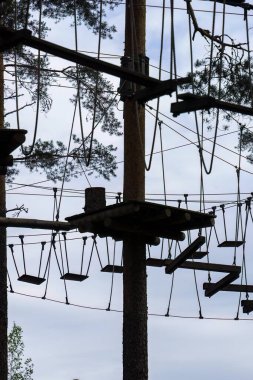 Platformlu yüksek ipler ve gökyüzüne karşı siluetlenmiş salıncaklar. Hyvinkaa, Finlandiya.