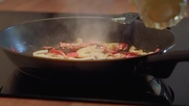 Omlet pişirmek, jambon ve soğanlı çırpılmış yumurtaları tavaya dökmek.