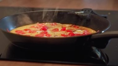 Tavada pişirirken omlet üzerine peynir serpiyorum.