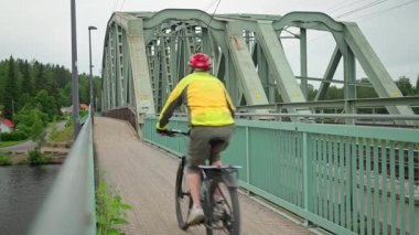 Hameenlinna, Finlandiya. 27 Haziran 2025 - Vanajavesi demiryolu köprüsünden geçen bisikletçiler