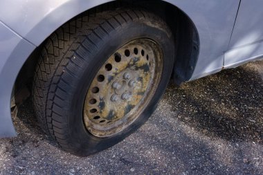 Close-up of a flat tire on a parked car.