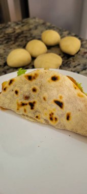 Et ve salatayla doldurulmuş tortilla, arka planda peynir.