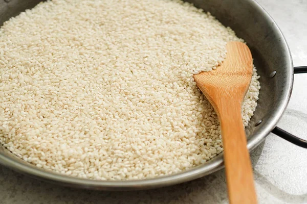 White rice and wooden rice scoop in paella pans