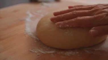woman sprinkling flour on the dough and rolling it out with a rolling pin