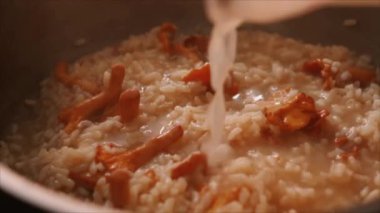 Şef İtalyan mantarlı risotto (risotto ai funghi) hazırlarken bir yandan da bouillon ekliyor.