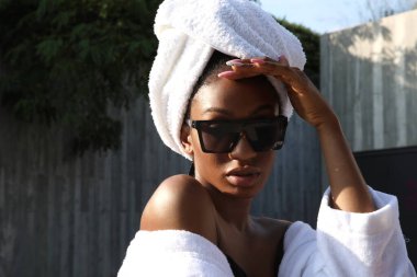 Beyaz havluya sarılı açık havada poz veren Afro-Amerikalı genç bir kadının portresi. Yüksek kalite fotoğraf.