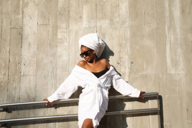 Beyaz havluya sarılı açık havada poz veren Afro-Amerikalı genç bir kadının portresi. Yüksek kalite fotoğraf.