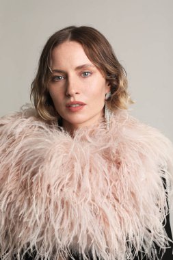 Beyaz duvarın önünde şık bir parti elbisesi içinde şık, zarif bir kadın poz veriyor. Makyajlı, güzel, şehvetli bir kadın. Yüksek kalite fotoğraf