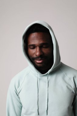 Kapüşonlu genç adamın kapalı mekanda poz verirken yakın çekimi. Dikey maket. Yüksek kalite fotoğraf.