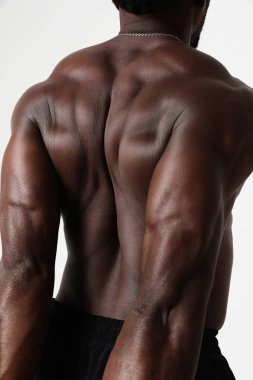 Dambıllarla antrenmandan sonra dinlenen sportif adam. Çıplak gövdeli atletik bir adamın fotoğrafı ve gri arka planda iyi bir fiziği var. Güç ve motivasyon. Yüksek kalite fotoğraf