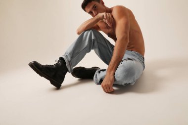 Caucasian young man shirtless posing on white background. Vertical. High quality photo.