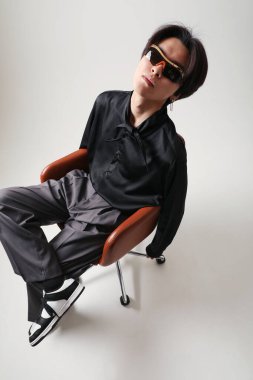 Confident young Asian man posing indoor sitting over white background. Mock-up. High quality photo.