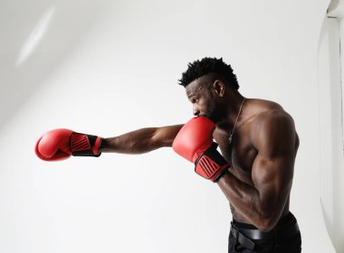 İyi fiziği olan atletik genç adam kırmızı eldivenli boks yapıyor. - Evet. Yüksek kalite fotoğraf.
