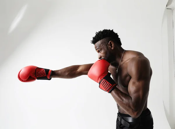 Athletic young man with good physique body condition boxing with red gloves. . High quality photo.