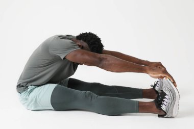 Atletik genç adam beyaz duvar üzerinde kas esneme egzersizleri yapıyor. Dikey. Yüksek kalite fotoğraf.