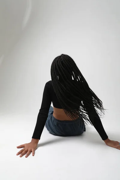 Back view of African American woman with long braids, posing at studio. Mock-up. High quality photo.