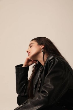 Stüdyoda motosiklet ceketi giymiş genç ve güzel bir kadının dikey görüntüsü. Dikey maket. Yüksek kalite fotoğraf.
