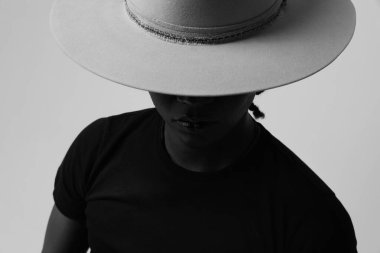 Yakışıklı ve kaygısız esmer tenli, modaya uygun gri şapkalı genç adam. İzole edilmiş. Yüksek kalite fotoğraf. Siyah ve beyaz.