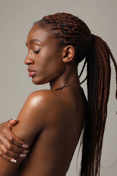 Young African American woman with gorgeous long braids posing on white wall. Vertical. High quality photo.