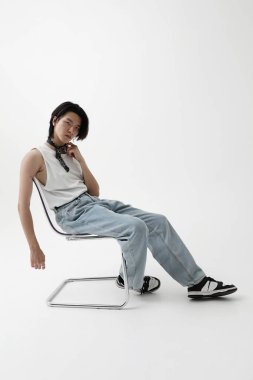 Beyaz arka planda kapalı alanda poz veren kendinden emin bir Asyalı. Dikey maket. Yüksek kalite fotoğraf.