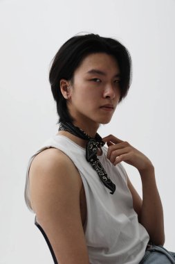 Beyaz arka planda kapalı alanda poz veren kendinden emin bir Asyalı. Dikey maket. Yüksek kalite fotoğraf.