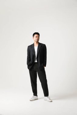 Siyah takım elbiseli gülümseyen genç Asyalı işadamı beyaz arka planda izole edilmiş. Yüksek kalite fotoğraf